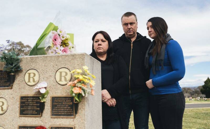 IN MOURNING: Mark Knowles, brother of murdered woman Patricia Riggs, with his wife Tracy and daughter Ashley, with the plaques at Queanbyean Lawn Cemetery for his mother, Carol Saxton, and his sister, Patricia Riggs whose ex-husband was charged with her murder 15 years after her disappearance. Photo: Rohan Thomson.
