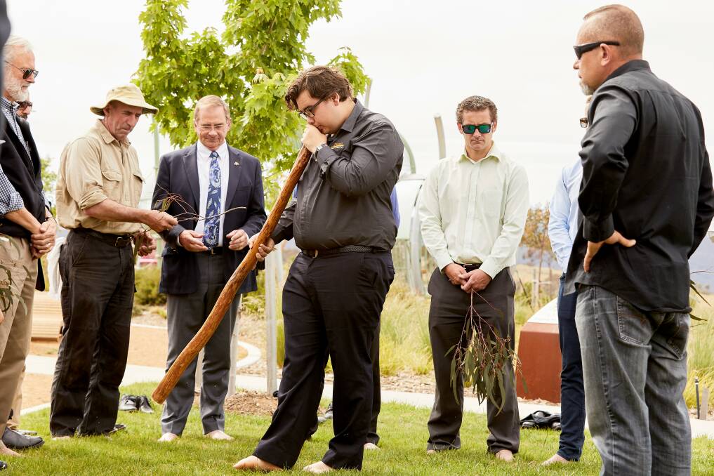 Didgeridoo player Jayden Goodrem performs as guests, including Mayor Tim Overall and Councillor Pete Harrison, cleanse themselves with gum leaves in a barefoot ceremony. Photo: Supplied