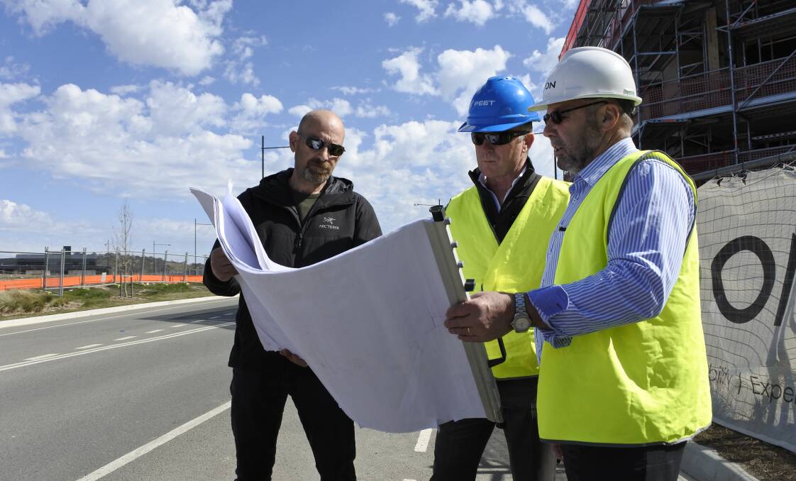IGA owner John Efkarpidis, Googong project director Malcolm Leslie and Iqon project director Peter Naylor examine plans for the new North Village Centre.