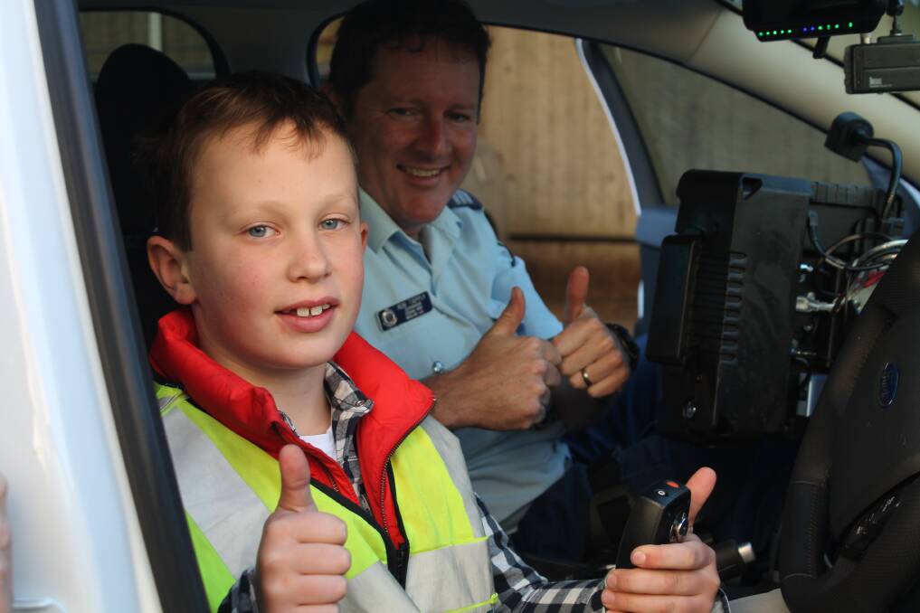 Seven-year old Queanbeyan boy Eddie Marcks enjoys his time in a NSW Police highway patrol cruiser with officer Rob Tapply last Thursday-week. 								 Photo: Joshua Matic.