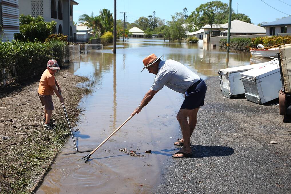 Residents clean up debris in their street as parts of southern Queensland experiences record flooding in the wake of Tropical Cyclone Oswald on January 30, 2013 in Bundaberg, Australia. Photo by Chris Hyde/Getty Images