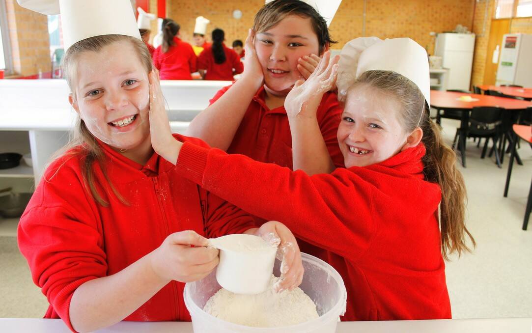 Queanbeyan South Public School students Katelyn Skilton, Turell Mapiva-Miller and Taya Ison getting their hands dirty in the school's new kitchen.