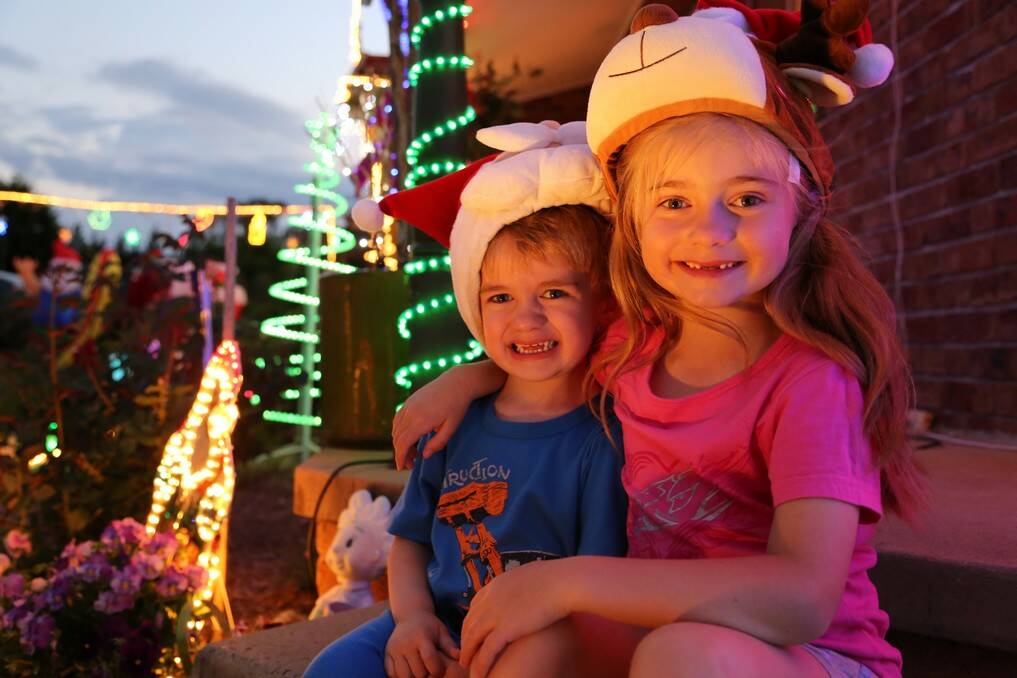 Luke, 3 and Chloe Amey, 6 sit among the Christmas lights display at their Queanbeyan home. 
