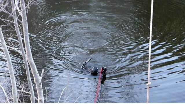 A police diver emerges from the Queanbeyan River holding a gun. Photo: Troy Roberts
