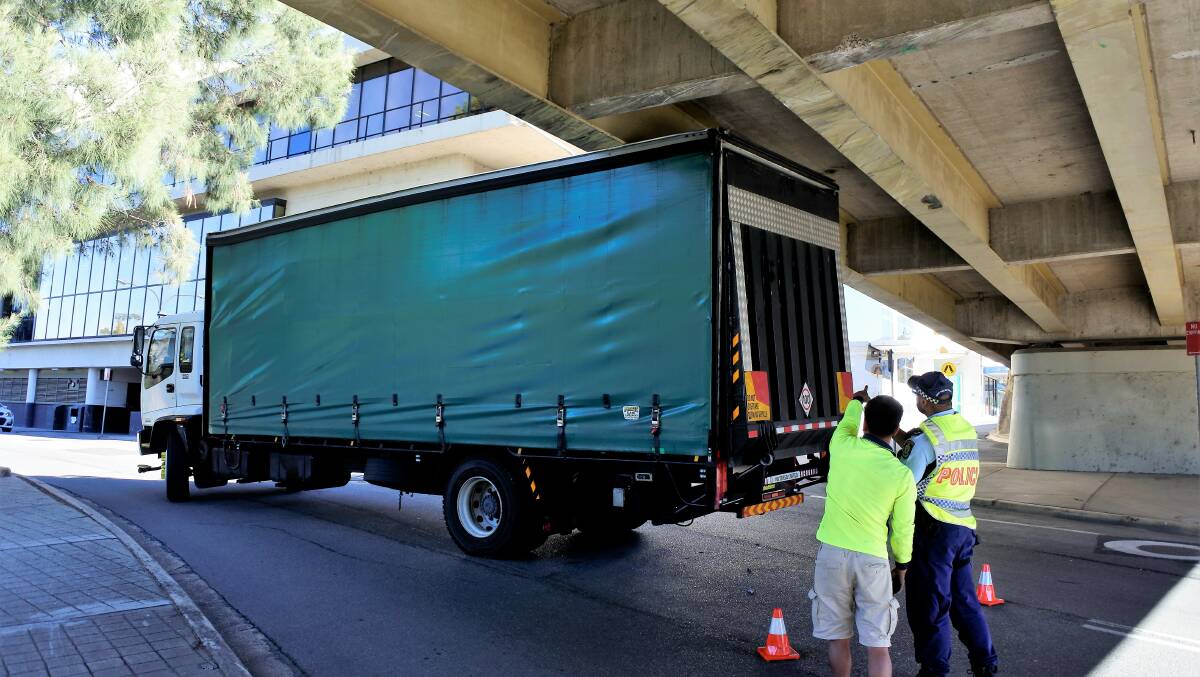 Police and the driver inspect the truck stuck under Queens Bridge. Photo: Elliot Williams