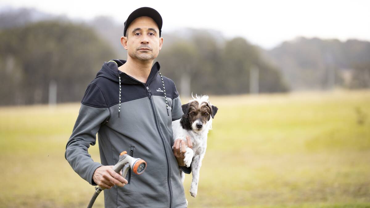 Jash Barber, with his dog Charlie, spent an anxious night surrounded by the glow of fire on all three hill sides surrounding his Bawley Point home. Picture: Sitthixay Ditthavong