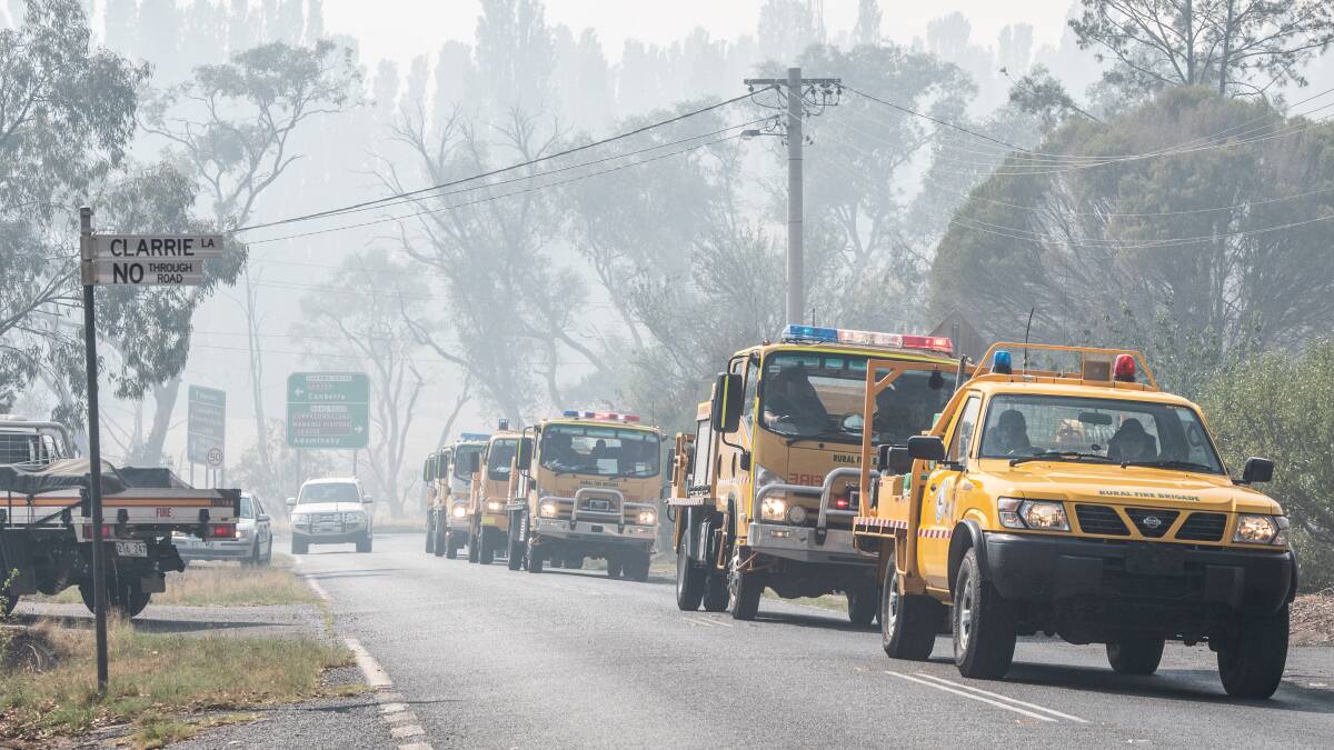 A strike force of Queensland Fire Service volunteers working on the Orroral fires drive through Tharwa village. PIcture: Karleen Minney