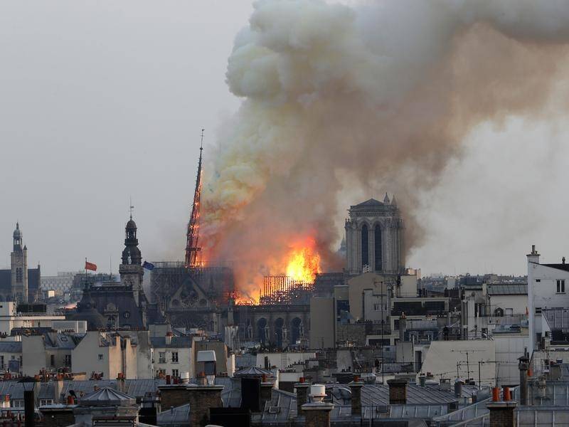 Notre Dame cathedral has gone up in flames; the spire and roof have collapsed; a tower is alight.