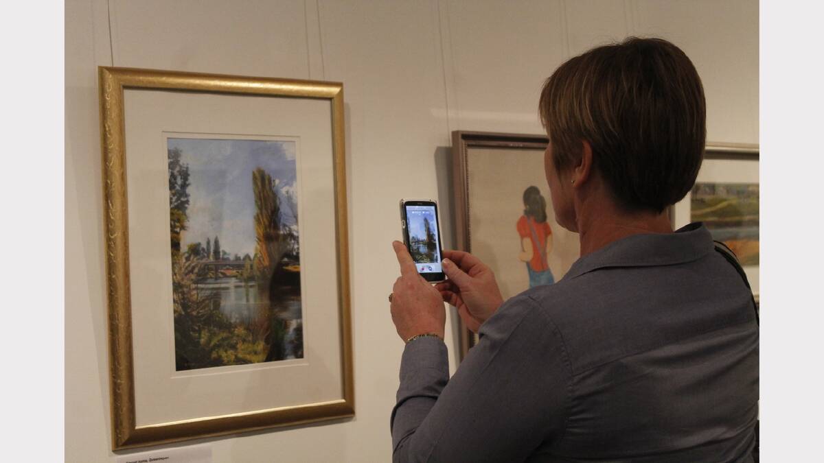 A spectator captures an entry into the 2013 QCC Regional Art Awards.